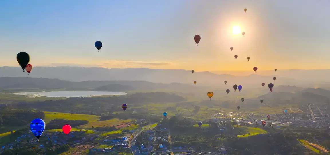 Balões em voo sobre a paisagem de Torres ao pôr do sol