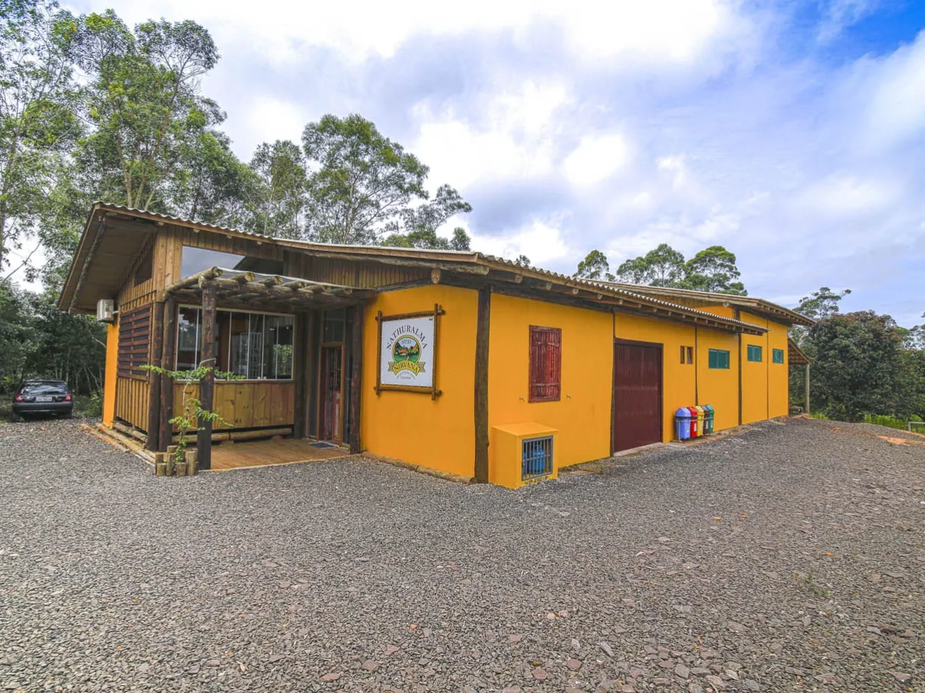 Fachada do Sítio Nirvana, com entrada de madeira e paredes amarelas
