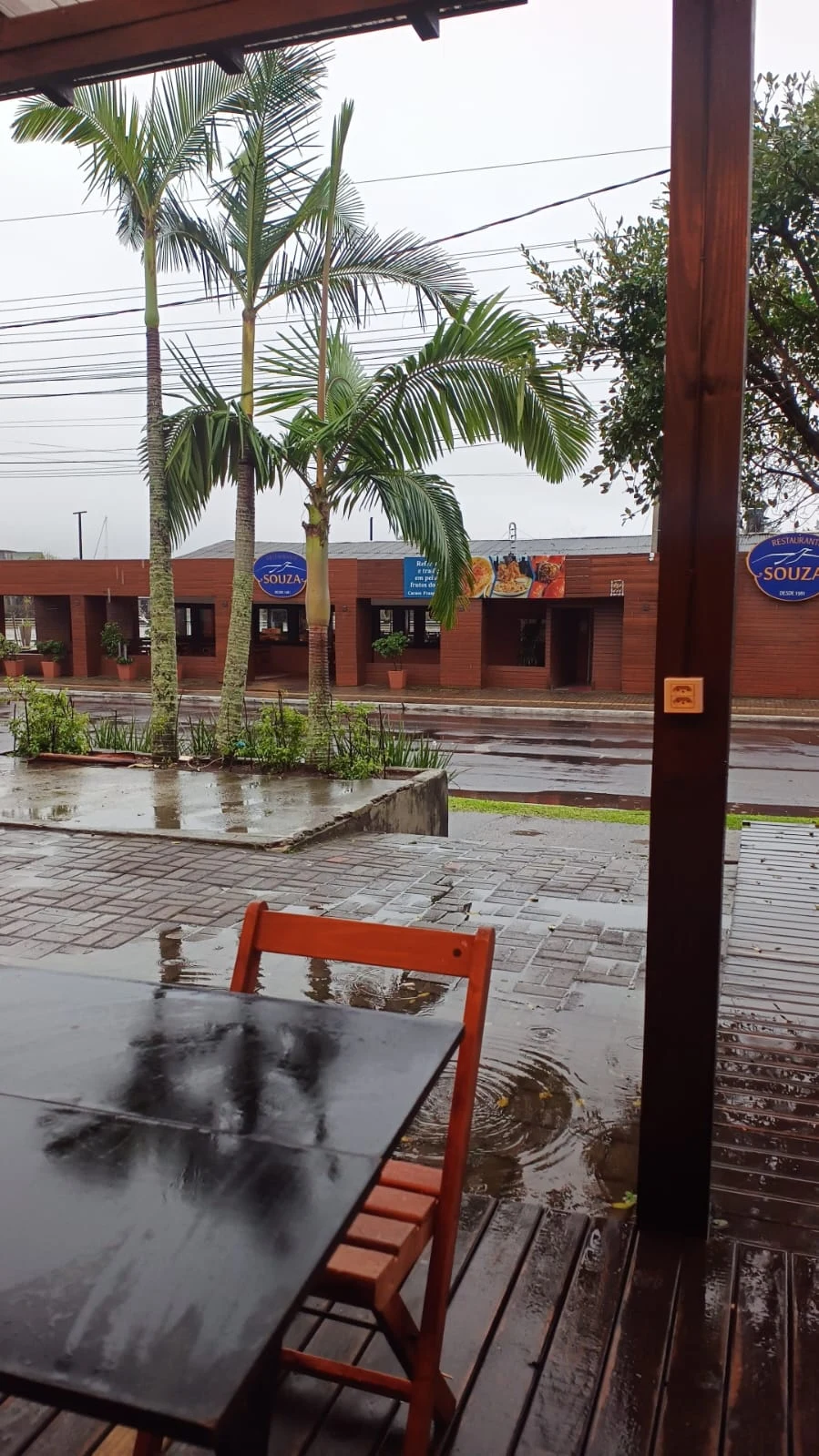 Área externa coberta e fachada do Restaurante Souza em dia de chuva