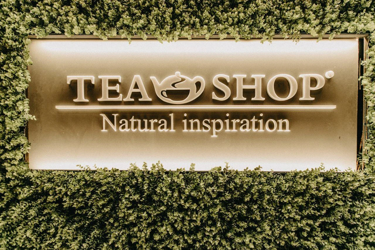 Placa da Tea Shop em parede com vegetação
